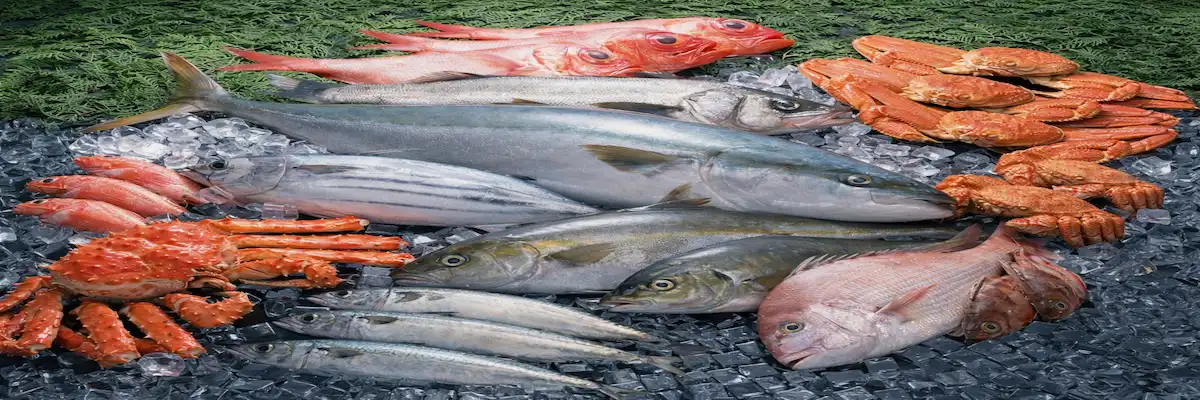 Fresh seafood assortment including whole fish and crabs displayed on crushed ice